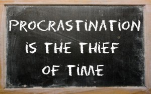 Proverb "Procrastination is the thief of time" written on a blac